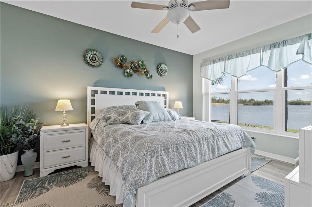 Image 2: Bedroom with light wood-style floors, ceiling fan, and a water view