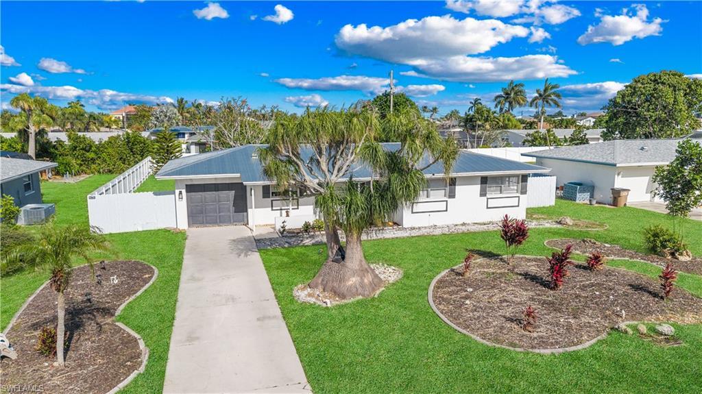 Image 1: The property features a well-maintained front yard with a concrete driveway, established landscaping, and a fenced perimeter