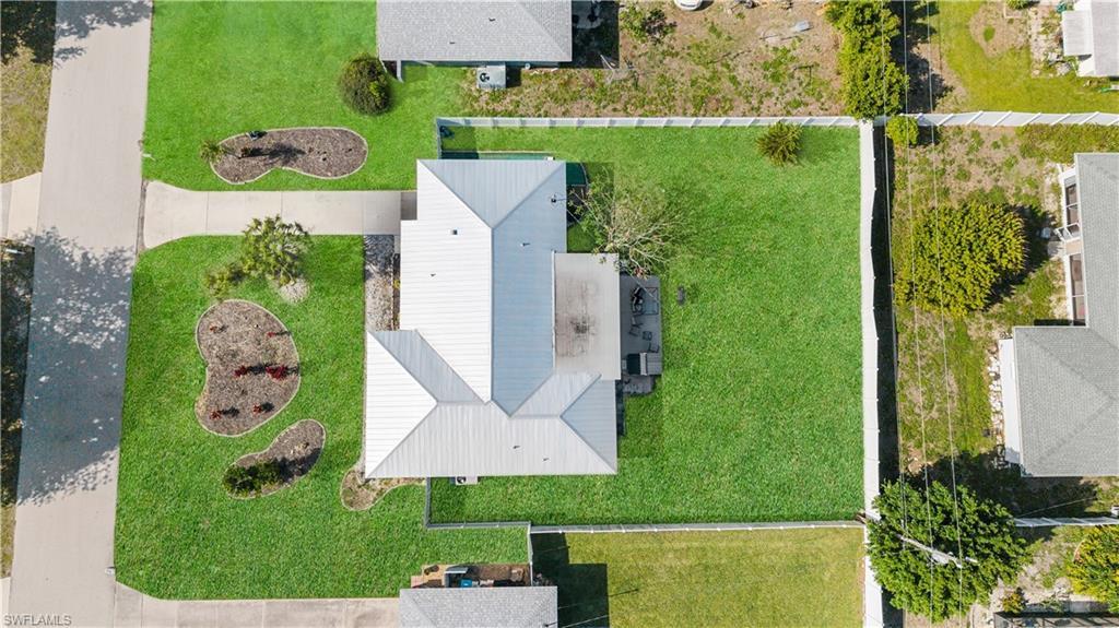 Image 2: An aerial view showcases the property's expansive, well-maintained lawn, complemented by a white-fenced perimeter