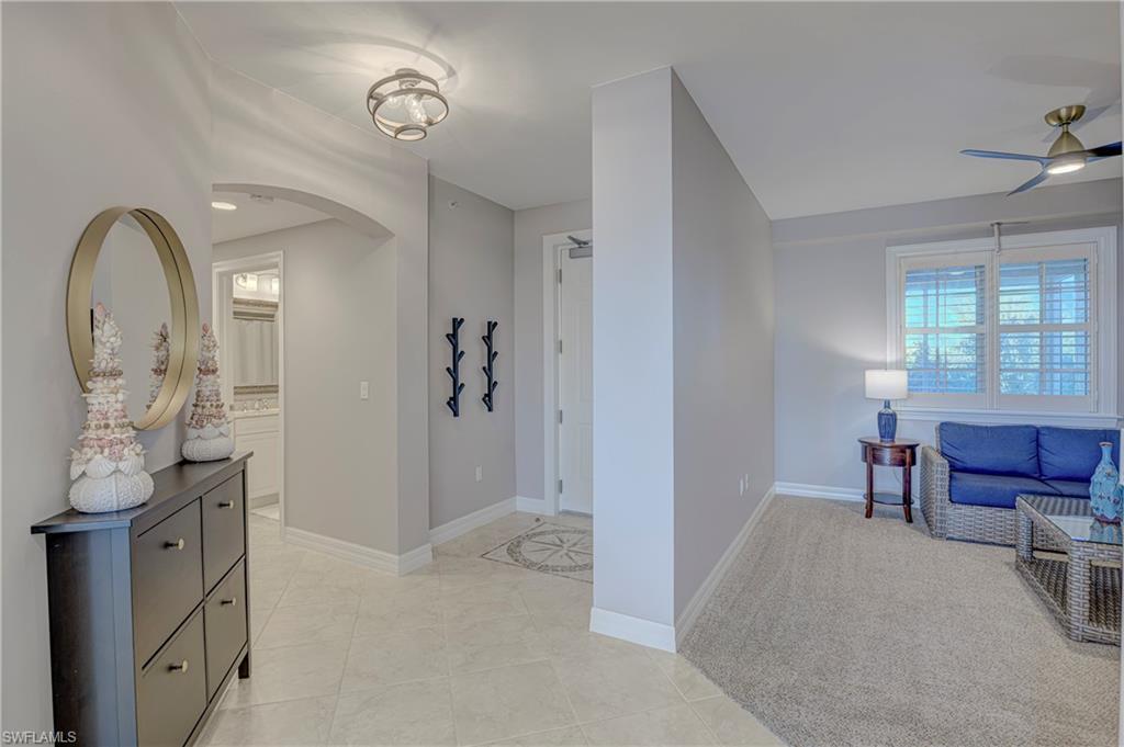 Image 2: Travertine tile flooring in the entry hall featuring an arched doorway and a flush mount light fixture