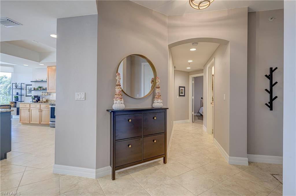 Image 4: Hallway with tile flooring and recessed lighting, featuring an arched entryway and light neutral wall paint