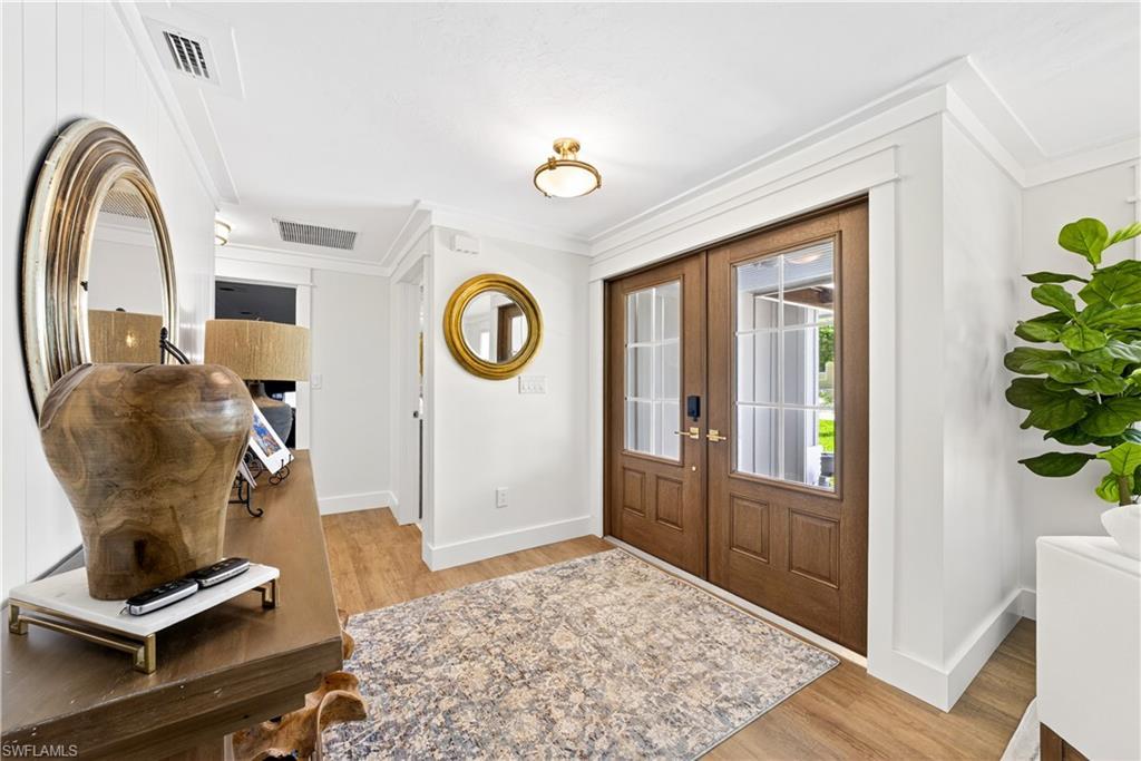 Image 2: Entryway featuring double wood-paneled doors with glass inserts, wood-finish flooring, and crown molding