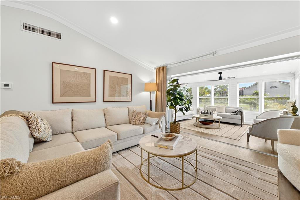 Image 4: Spacious living area featuring vaulted ceilings with crown molding, wood-finish flooring, and ample natural light from multiple windows