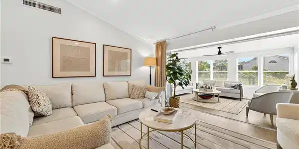 Image 4: Spacious living area featuring vaulted ceilings with crown molding, wood-finish flooring, and ample natural light from multiple windows