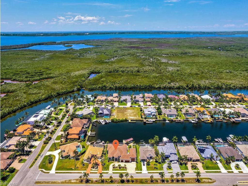 Image 2: Aerial perspective showcasing a waterfront community with canal access, mature landscaping, and a distant body of water
