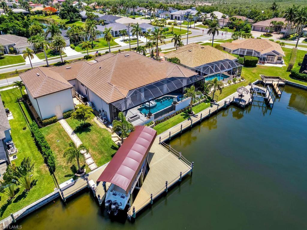 Image 3: Waterfront property featuring a screened-in pool area, tile roof, and a private dock with a boat lift
