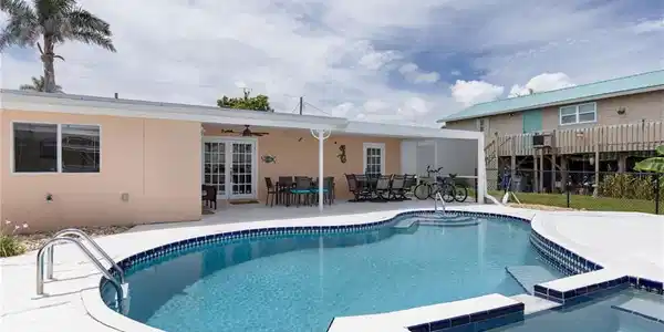 Image 3: Freeform swimming pool with integrated spa and surrounding white concrete deck