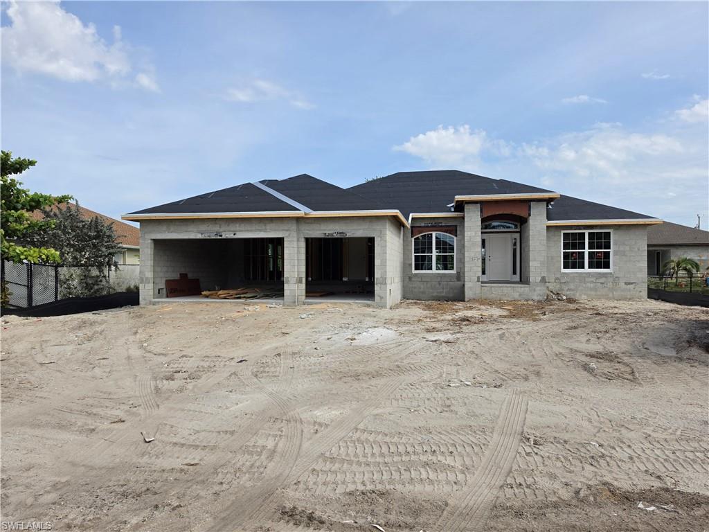 Image 1: Single-story block construction home under construction, featuring a dark shingled roof, a recessed entry with an arched accent, and multiple windows with white frames