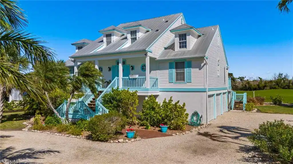 Image 1: Coastal inspired home featuring stairway, gravel driveway, covered porch, and a metal roof
