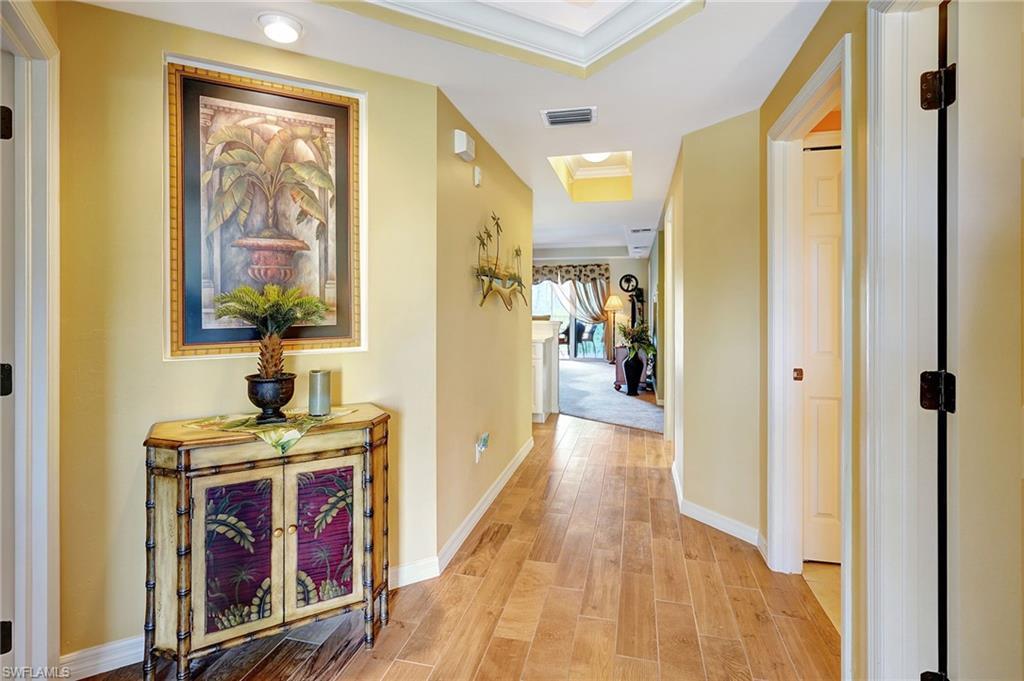 Image 1: Hall featuring visible vents, baseboards, ornamental molding, light wood-type flooring, and a raised ceiling