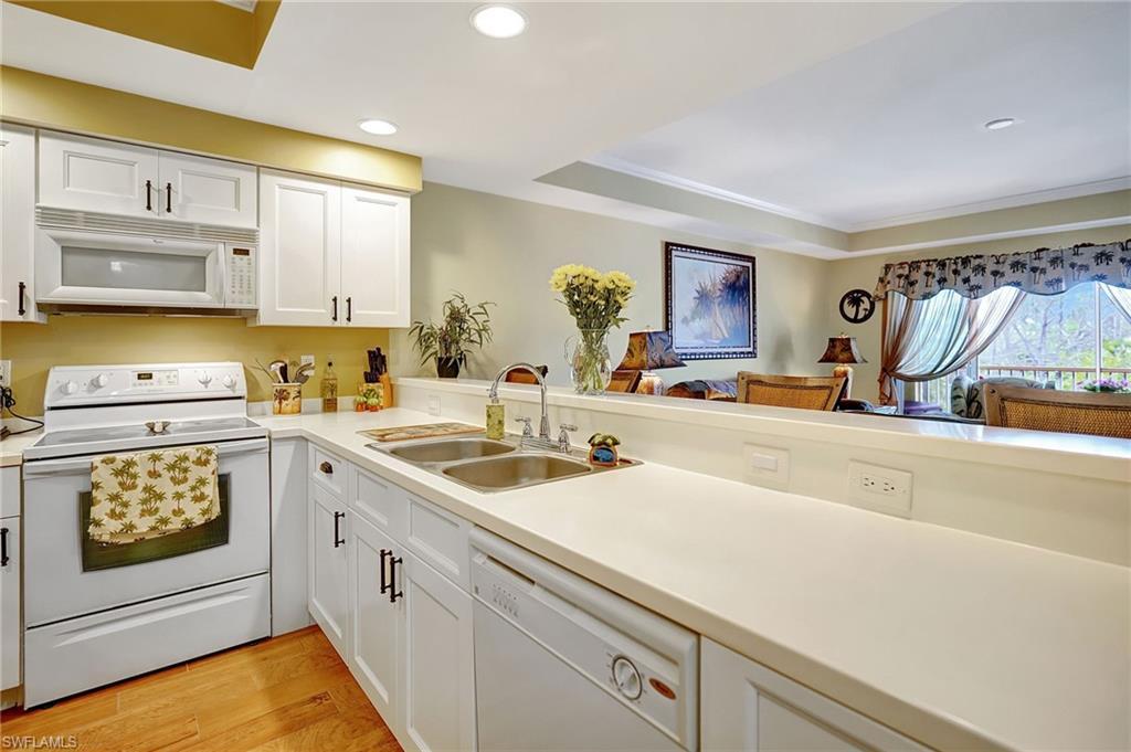 Image 3: Kitchen featuring white appliances, white cabinets, light countertops, light wood-type flooring, and a sink