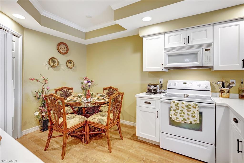 Image 4: Kitchen with light countertops, white appliances, white cabinetry, and crown molding