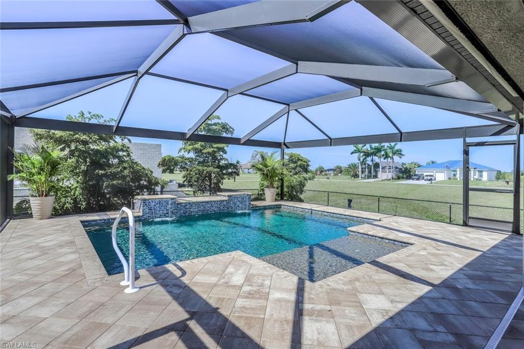 Image 2: Screened lanai featuring a swimming pool with a stone-clad waterfall and integrated spa