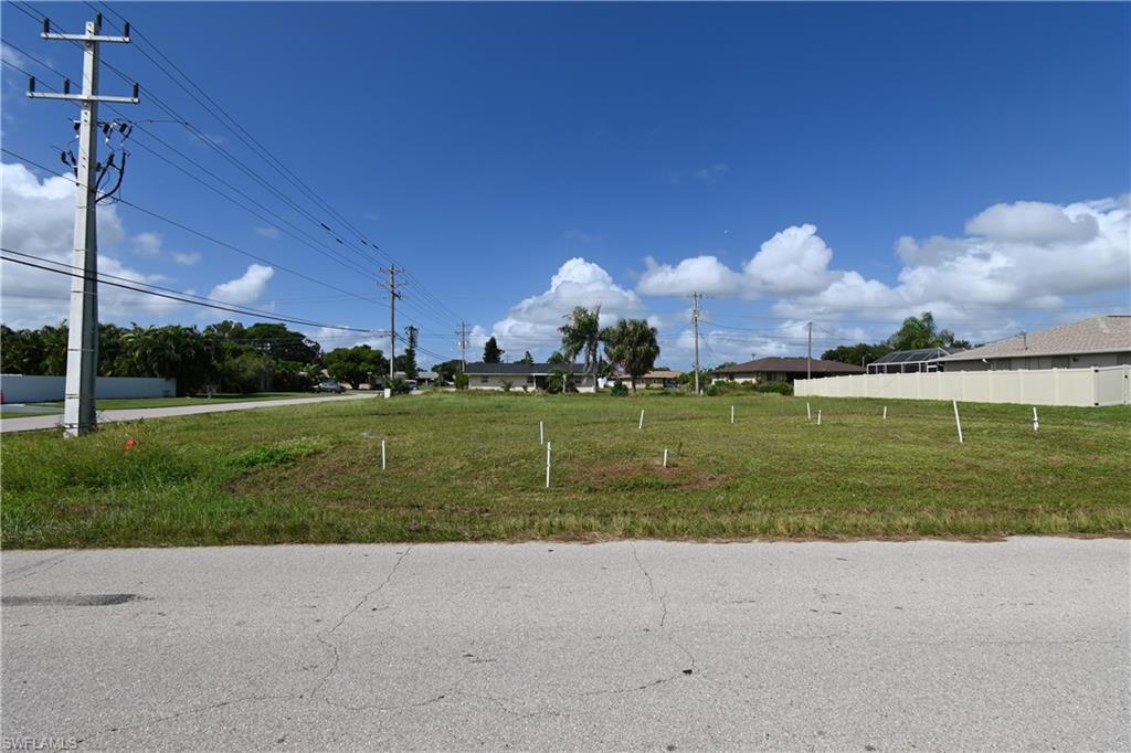 Image 2: Expansive cleared lot featuring level terrain, a partial rear privacy fence, and paved road frontage