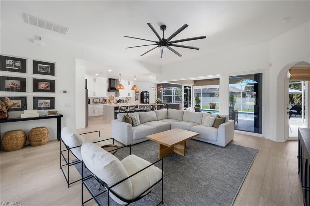 Image 3: Open-concept living space with light wood-finish flooring and a contemporary multi-blade ceiling fan