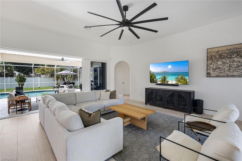 Image 4: Spacious living area featuring light-toned flooring, a large black ceiling fan, and an arched doorway