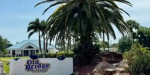 Image 4: Community entrance featuring a prominent sign, tropical landscaping with palm trees, and a multi-tiered rock waterfall