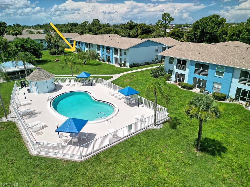 Image 1: Heart-shaped swimming pool with a surrounding paved deck, white perimeter fencing, and two blue shade canopies