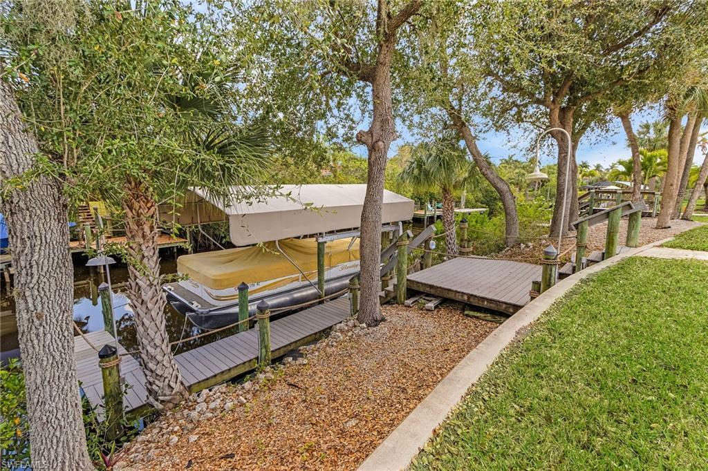 Image 3: Waterfront property featuring a covered boat lift, multiple docks, a waterside shower, and mature trees