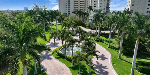 Image 4: View of property's attractive, unique pavers entrance featuring lush landscaping, water fountain, manned guard house and gates.