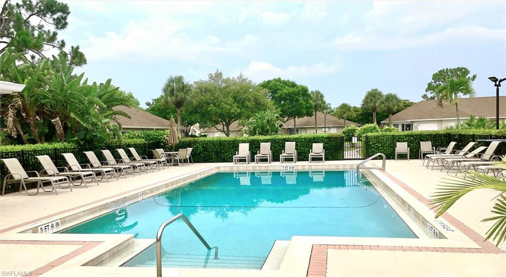 Image 2: Community swimming pool featuring a concrete deck with brick-patterned accents, multiple lounge chairs, and a black metal perimeter fence