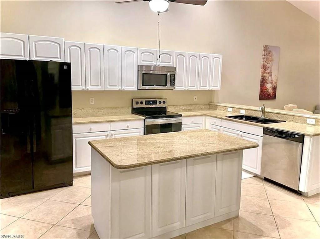 Image 3: Kitchen featuring an island, white cabinetry, integrated stainless steel appliances, light-toned countertops, and tile flooring