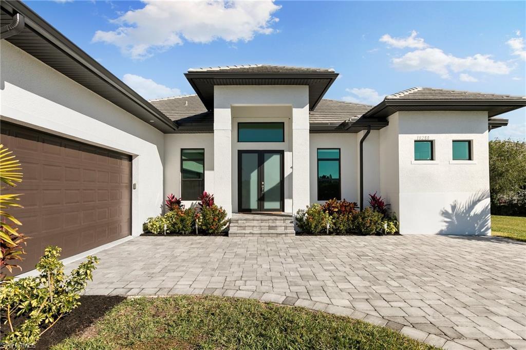 Image 2: View of front of property featuring stucco siding, a tiled roof, decorative driveway, and a garage