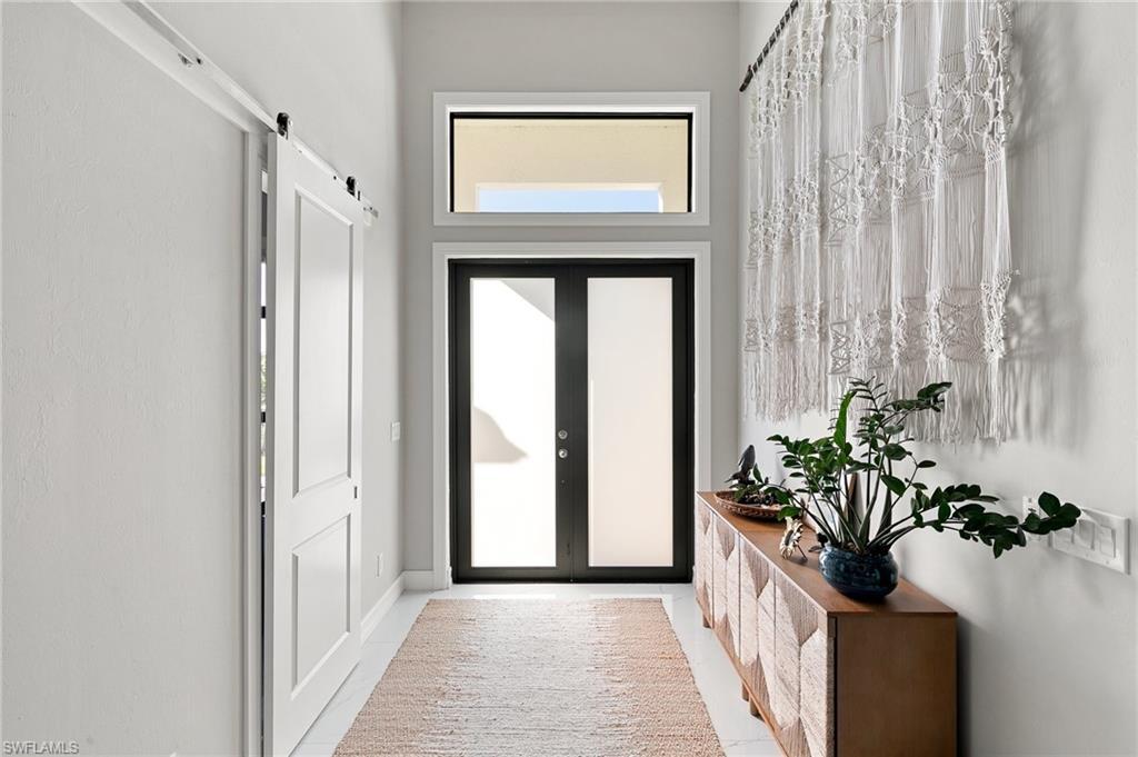 Image 3: Doorway to outside with a barn door, tile patterned flooring, and a high ceiling