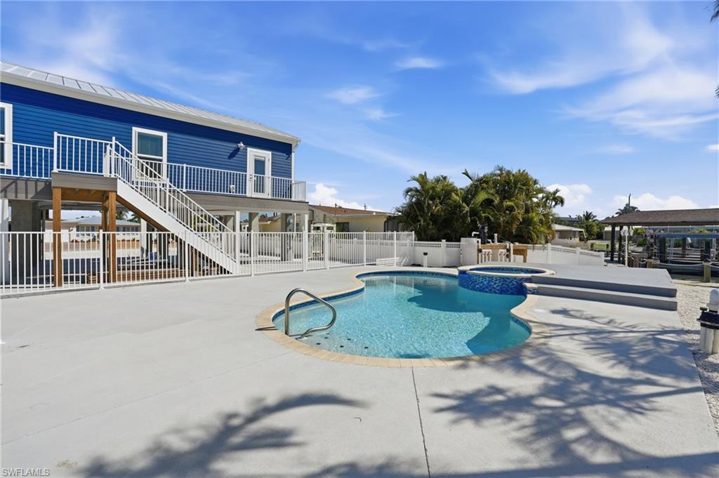 Image 3: Outdoor oasis featuring a freeform pool, integrated spa, and spacious concrete patio - Virtually Edited Image