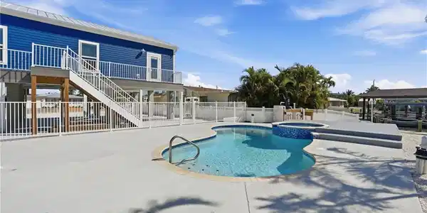 Image 3: Outdoor oasis featuring a freeform pool, integrated spa, and spacious concrete patio - Virtually Edited Image