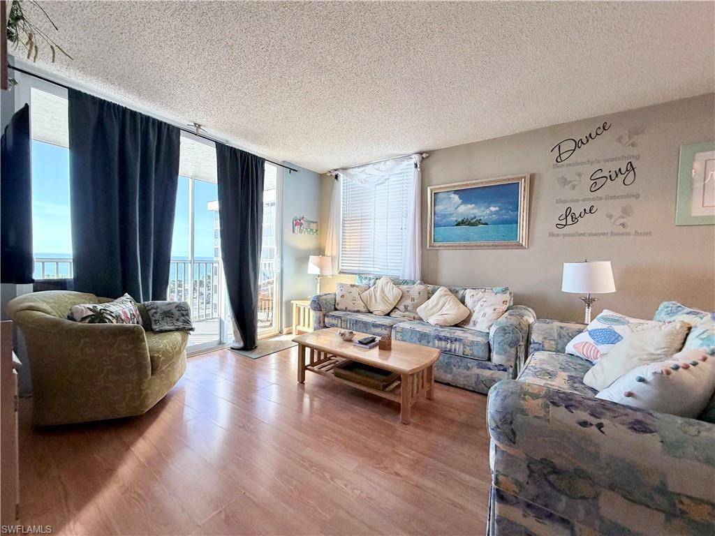 Image 3: Living area with a wall of windows, a textured ceiling, and wood finished floors