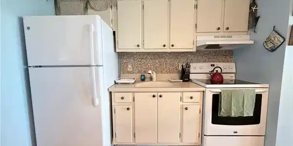 Image 4: Kitchen featuring white appliances, light countertops, decorative backsplash, under cabinet range hood, and light wood finished floors
