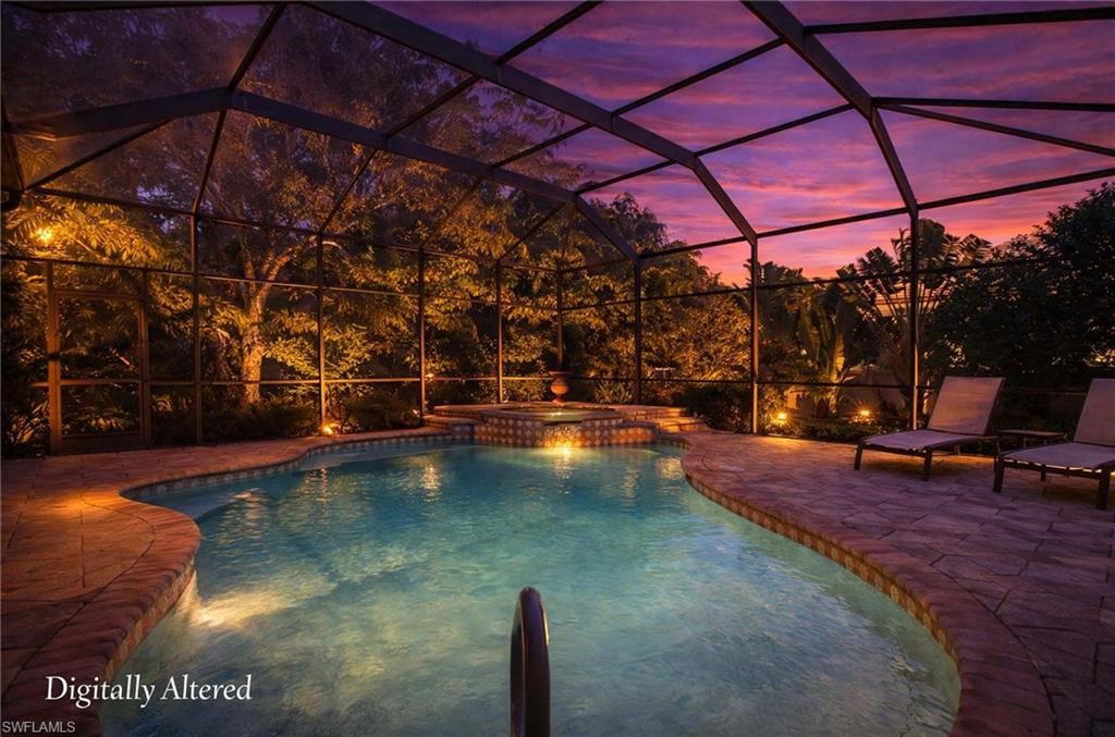 Image 2: Pool at dusk featuring glass enclosure, a pool with connected hot tub, and a patio area