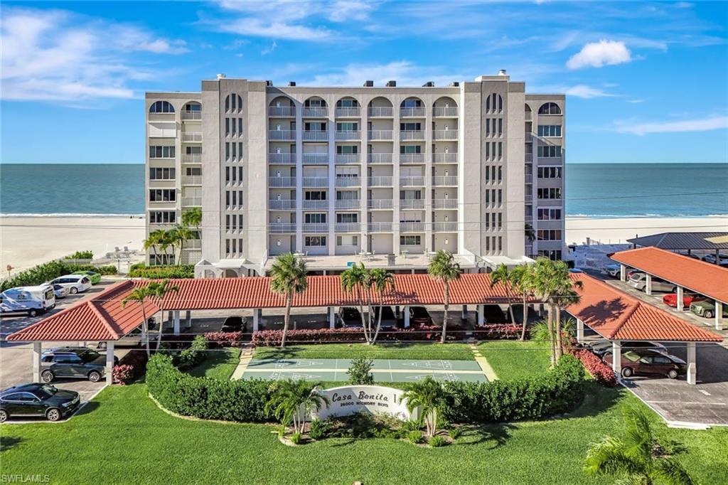 Image 4: View of apartment building / complex with view of water and beach and uncovered parking