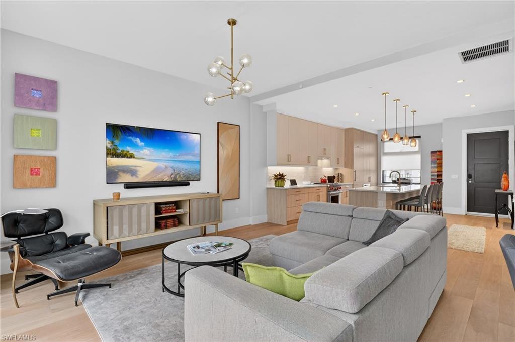 Image 3: Living room with a chandelier, light wood-type flooring, and recessed lighting