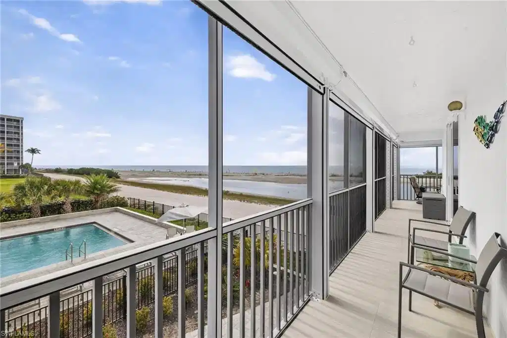 Image 1: South Facing side of the wrap around lanai, great view of community pool and the beach.  New Italian tile flooring along with new screens.