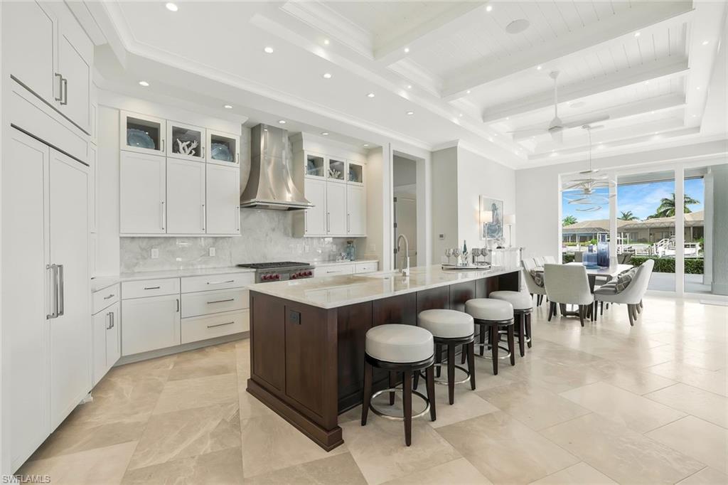 Image 3: Kitchen featuring light stone countertops, a spacious island, pendant lighting, a kitchen bar, and glass insert cabinets