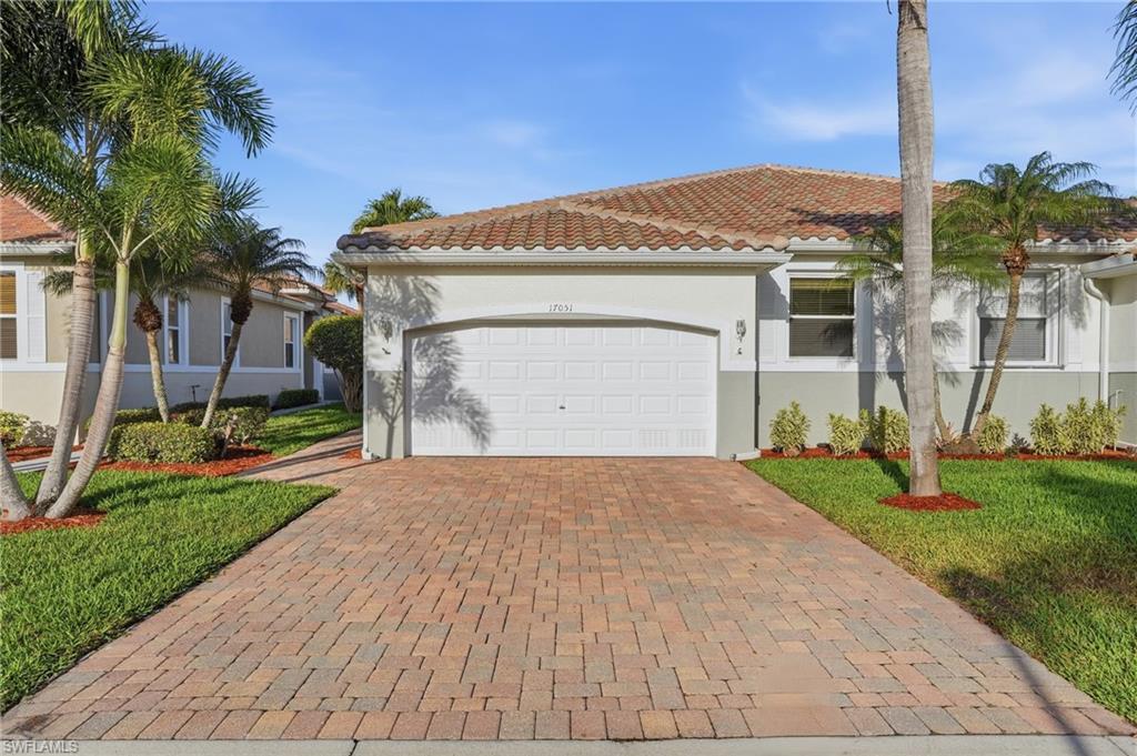 Image 1: Mediterranean / spanish-style house with decorative driveway, a tiled roof, an attached garage, stucco siding, and a front lawn - Virtually Edited Image