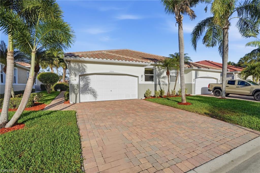 Image 2: View of front of house featuring stucco siding, decorative driveway, a front yard, a garage, and a tiled roof - Virtually Edited Image