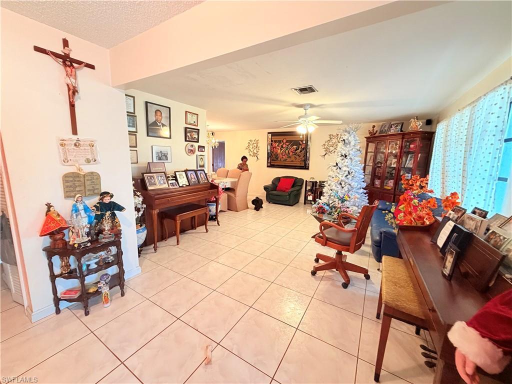 Image 4: Living area with ceiling fan, a textured ceiling, and light tile patterned floors