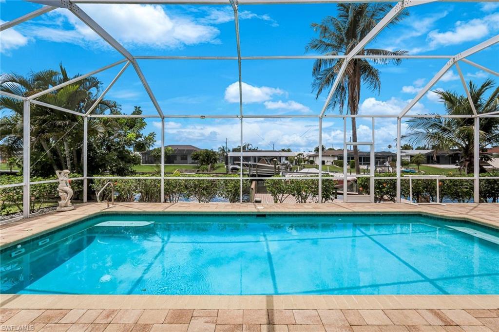 Image 3: Screened pool enclosure featuring a rectangular swimming pool with integrated steps, paver decking, and metal handrails