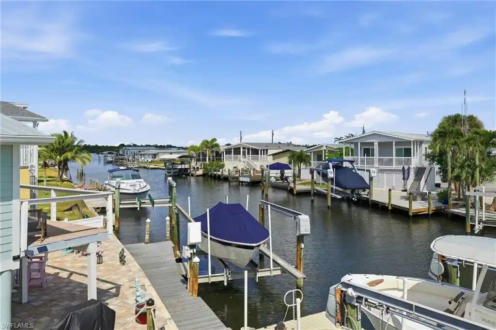 Image 1: Canal-front property featuring a private boat lift, extensive wooden decking, and mature palm trees