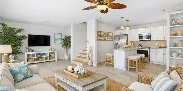 Image 2: Open-concept living space featuring wood-finish flooring, a contemporary kitchen with white cabinetry, stainless steel appliances, and a central island with bar seating