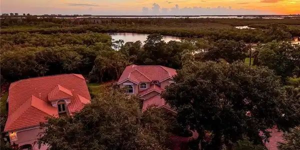 Image 2: Aerial perspective showcasing the property's red tile roof and surrounding lush foliage