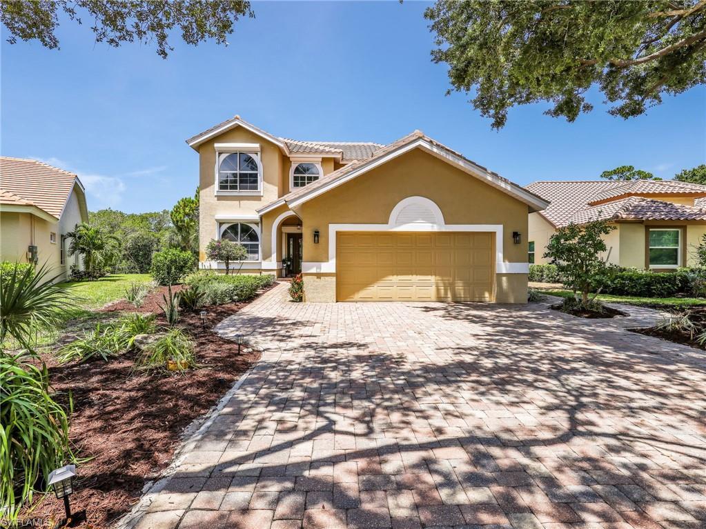 Image 3: Stucco exterior with a tiled roof, paver driveway, arched entryway, and landscaped garden beds