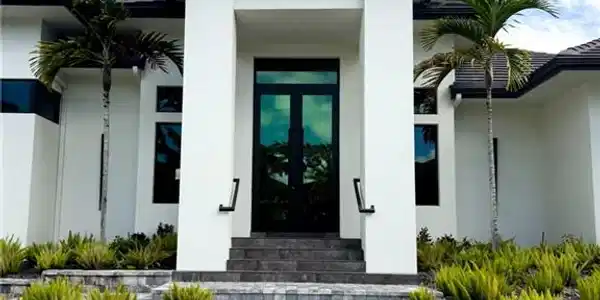 Image 2: Contemporary exterior with a prominent entry, dual dark-framed glass doors, and a paver walkway
