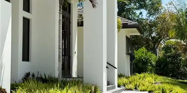 Image 4: Contemporary exterior with a prominent entry, dual dark-framed glass doors, and a paver walkway