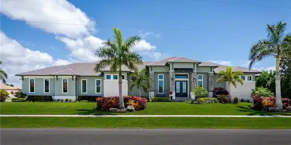 Image 3: Contemporary exterior with a light stucco finish, stone accents, and a covered entry