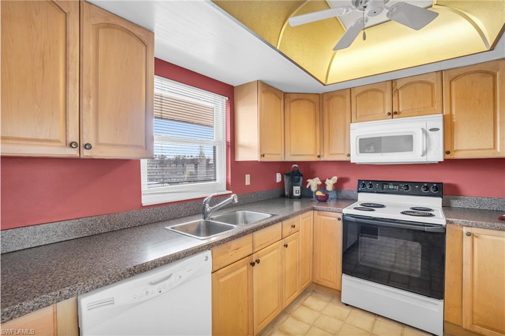 Image 4: UPDATED WARM WOOD CABINETRY, COORDINATING COUNTERS, AND NEWER IMPACT WINDOW...