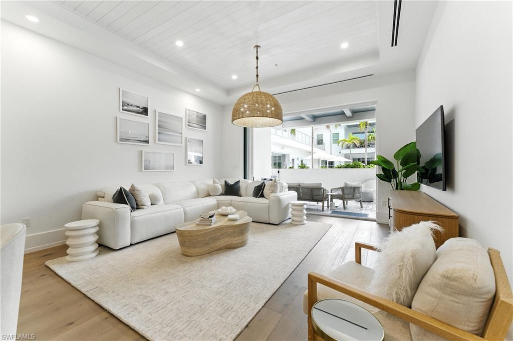 Image 1: Living room with light wood floors, recessed lighting, wood ceiling, and a tray ceiling